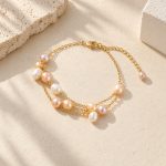 Triple-chain freshwater pearl bracelet with lobster clasp and pearl-tipped extender laid flat