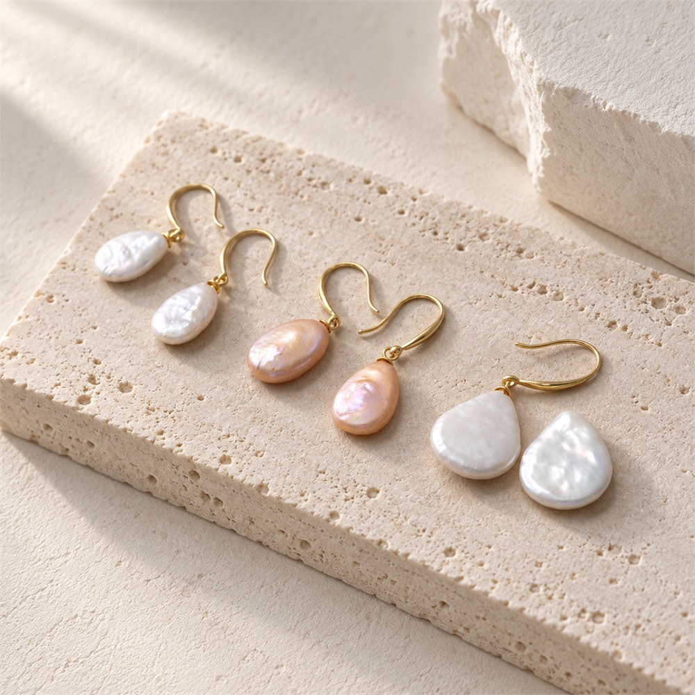 Three pairs of white and peach oval and teardrop pearl earrings with gold-toned hooks
