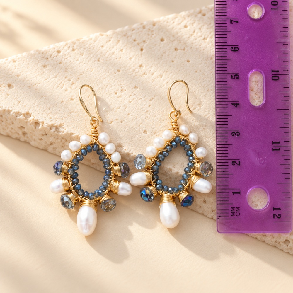 Blue crystal and pearl teardrop earrings placed beside a ruler