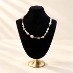 Shell fragment and freshwater pearl link necklace displayed on a black velvet bust