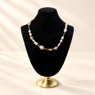 Shell fragment and freshwater pearl link necklace displayed on a black velvet bust
