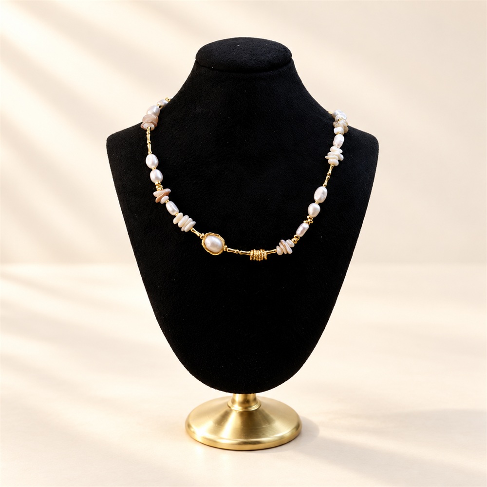 Shell fragment and freshwater pearl link necklace displayed on a black velvet bust