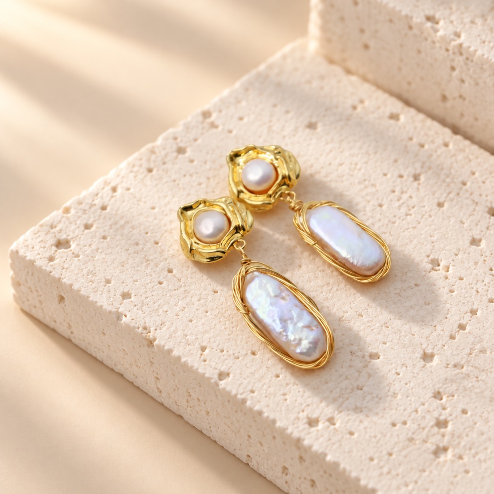 Close-up of irregular baroque pearl drops beneath textured golden stud settings