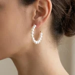 Freshwater pearl open hoop earring worn to show its curved silhouette