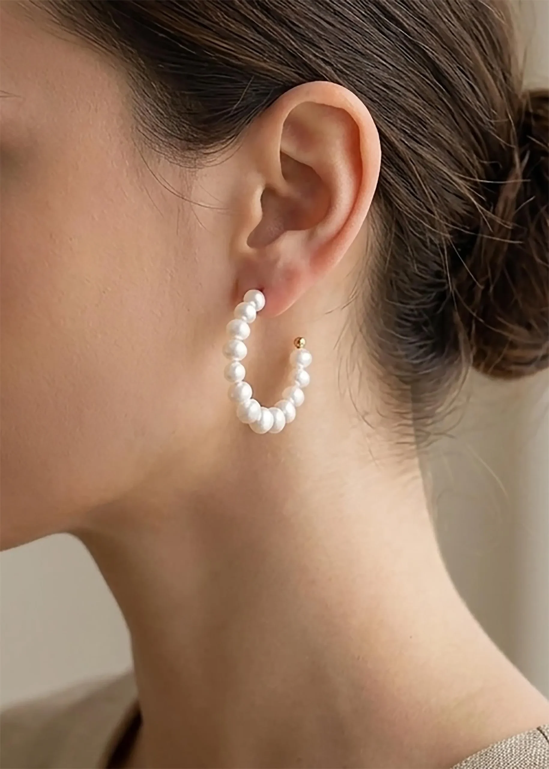 Freshwater pearl open hoop earring worn to show its curved silhouette