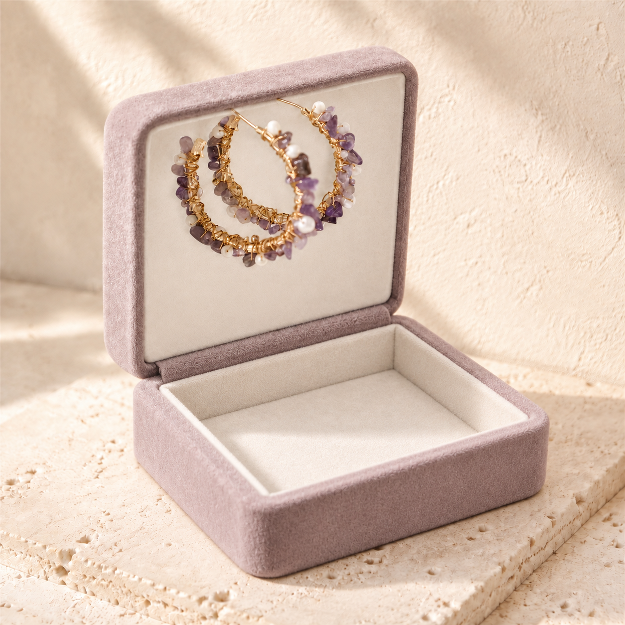 Amethyst and freshwater pearl hoop earrings displayed in an open mauve jewellery box