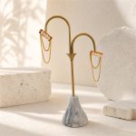 Pair of pearl bar chain tassel earrings hanging on a display stand