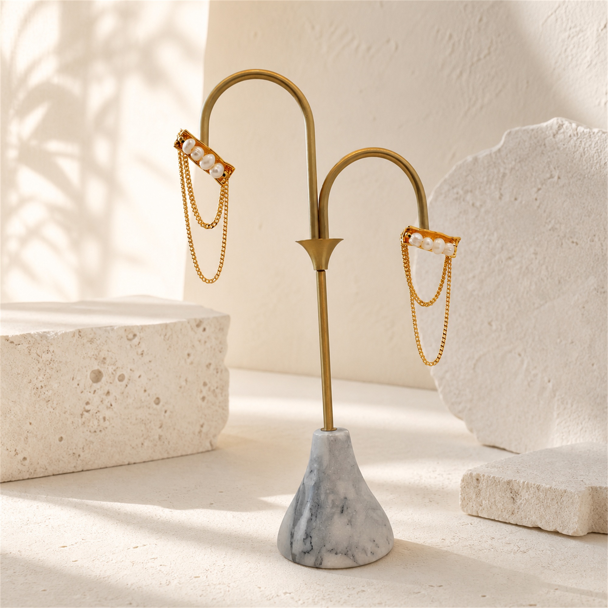 Pair of pearl bar chain tassel earrings hanging on a display stand