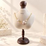 Asymmetrical baroque coin pearl and oval-link necklace on a display bust