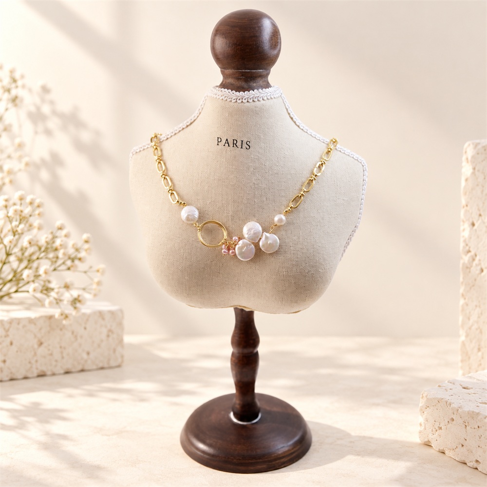 Asymmetrical baroque coin pearl and oval-link necklace on a display bust