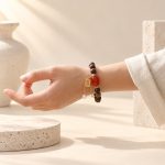 Sandalwood and red agate charm bracelet worn on a wrist