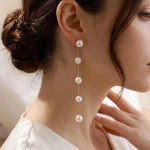 Model wearing a long five-pearl chain drop earring