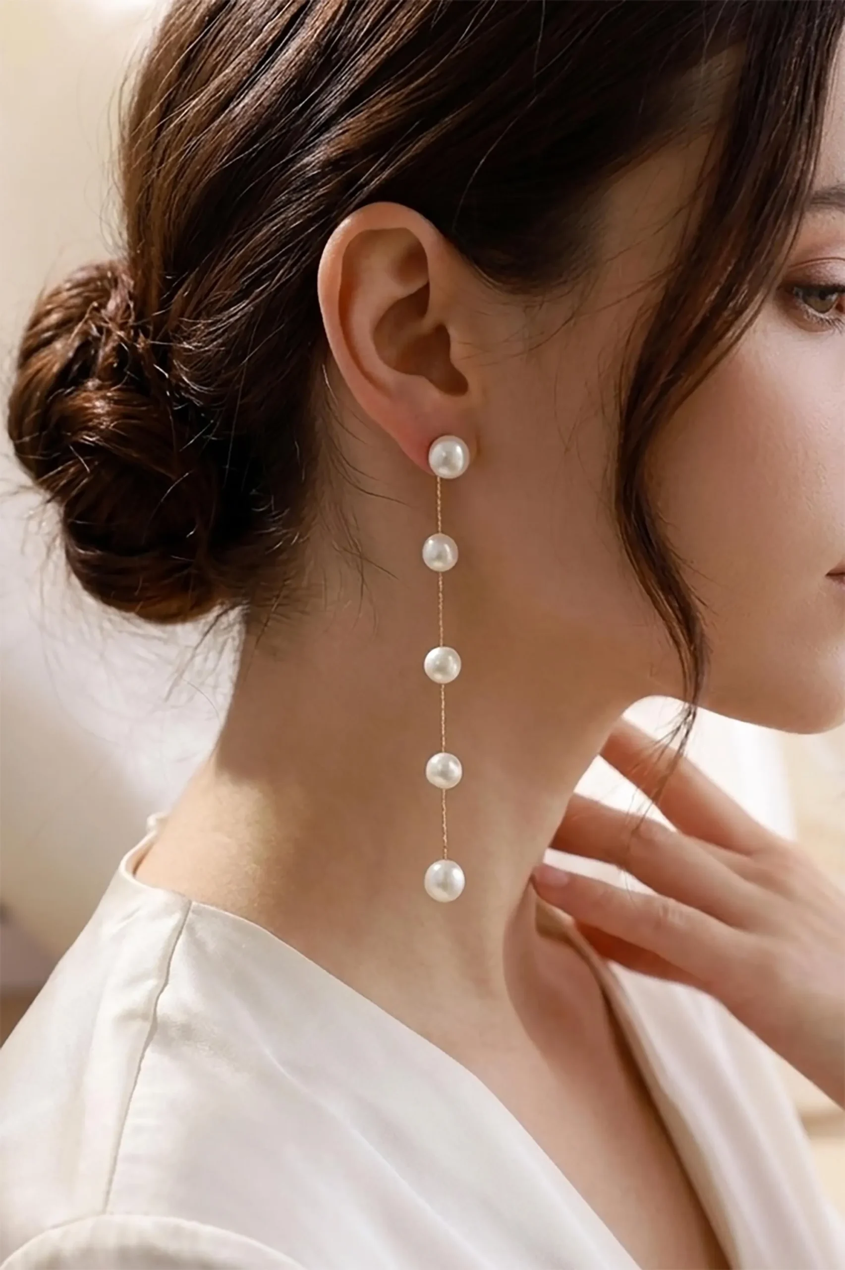 Model wearing a long five-pearl chain drop earring