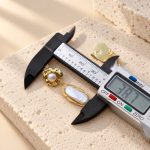 Baroque pearl drop earring shown beside a digital caliper