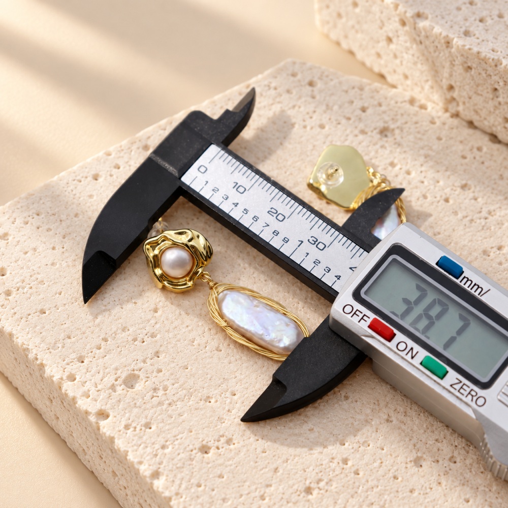 Baroque pearl drop earring shown beside a digital caliper