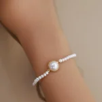 Bezel pearl bracelet worn on a wrist with small pearls along the strand