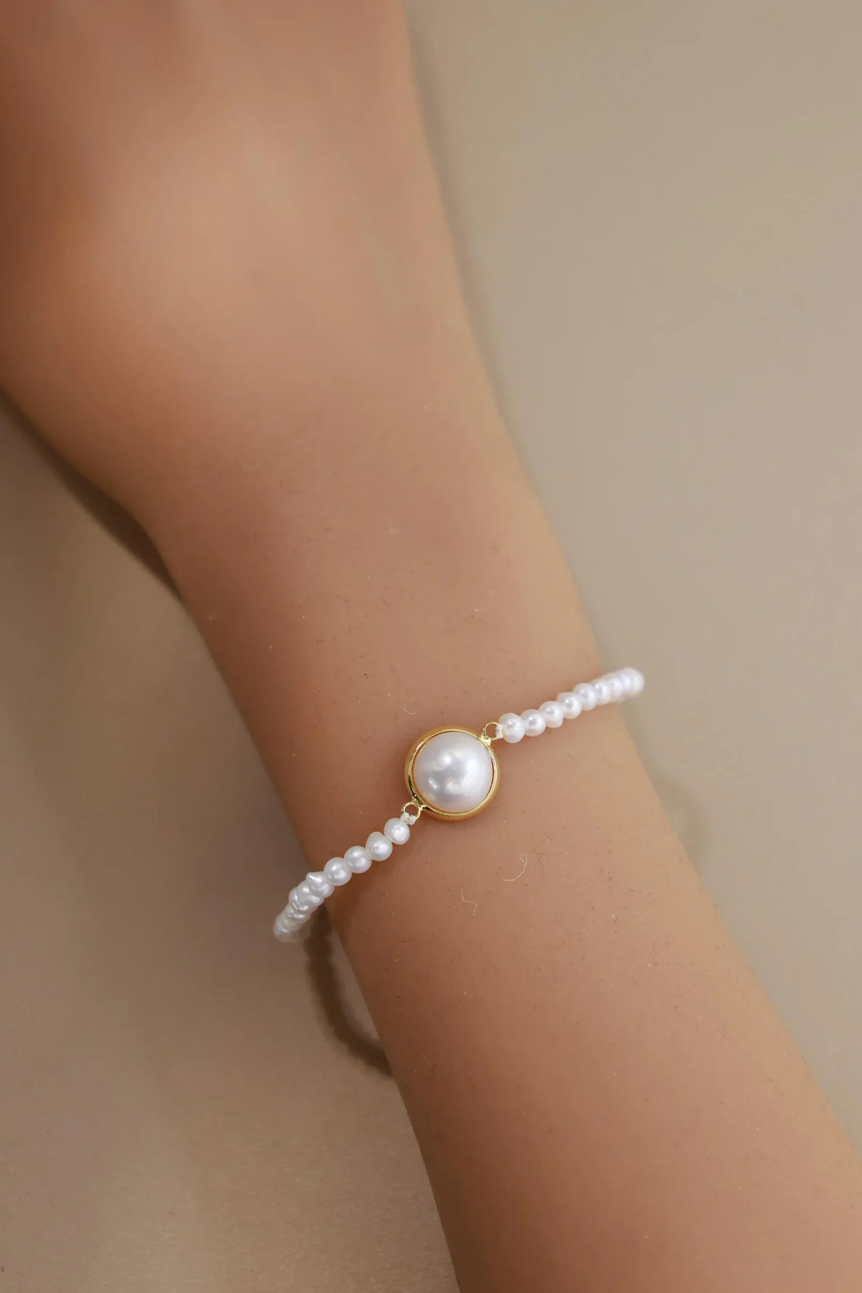 Bezel pearl bracelet worn on a wrist with small pearls along the strand