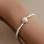 Angled wrist view of a fine freshwater pearl bracelet with a larger bezel-set pearl