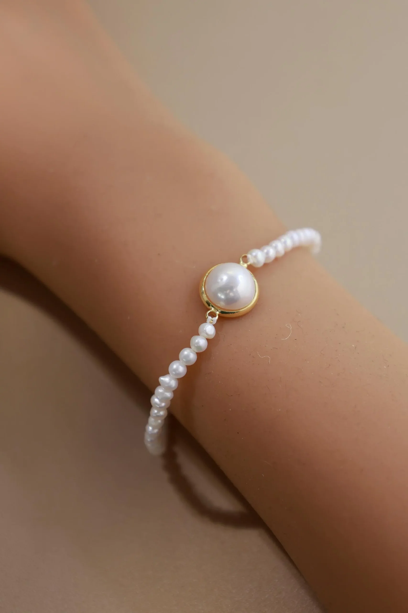 Angled wrist view of a fine freshwater pearl bracelet with a larger bezel-set pearl