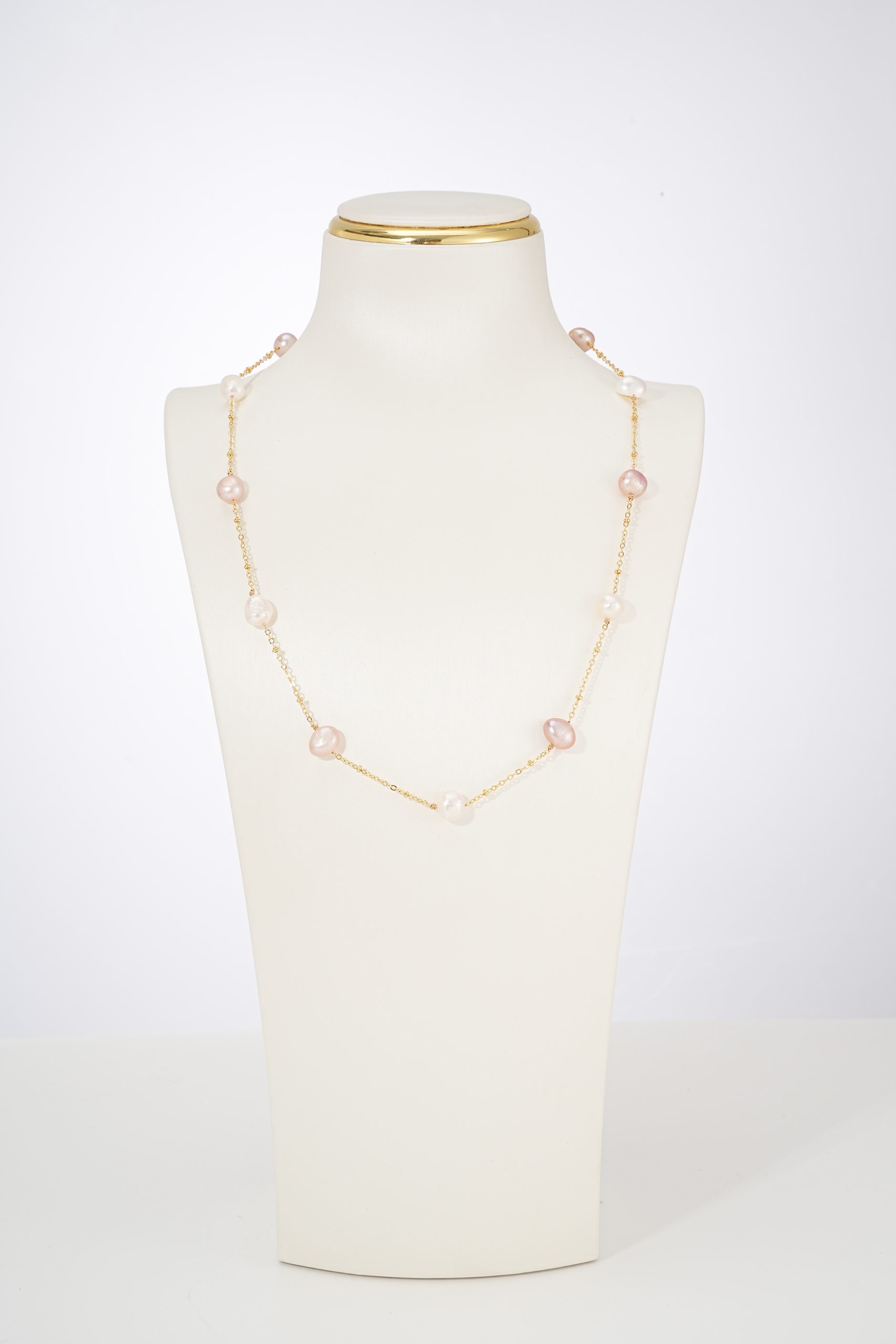 Pink and white freshwater pearl station necklace on a display bust