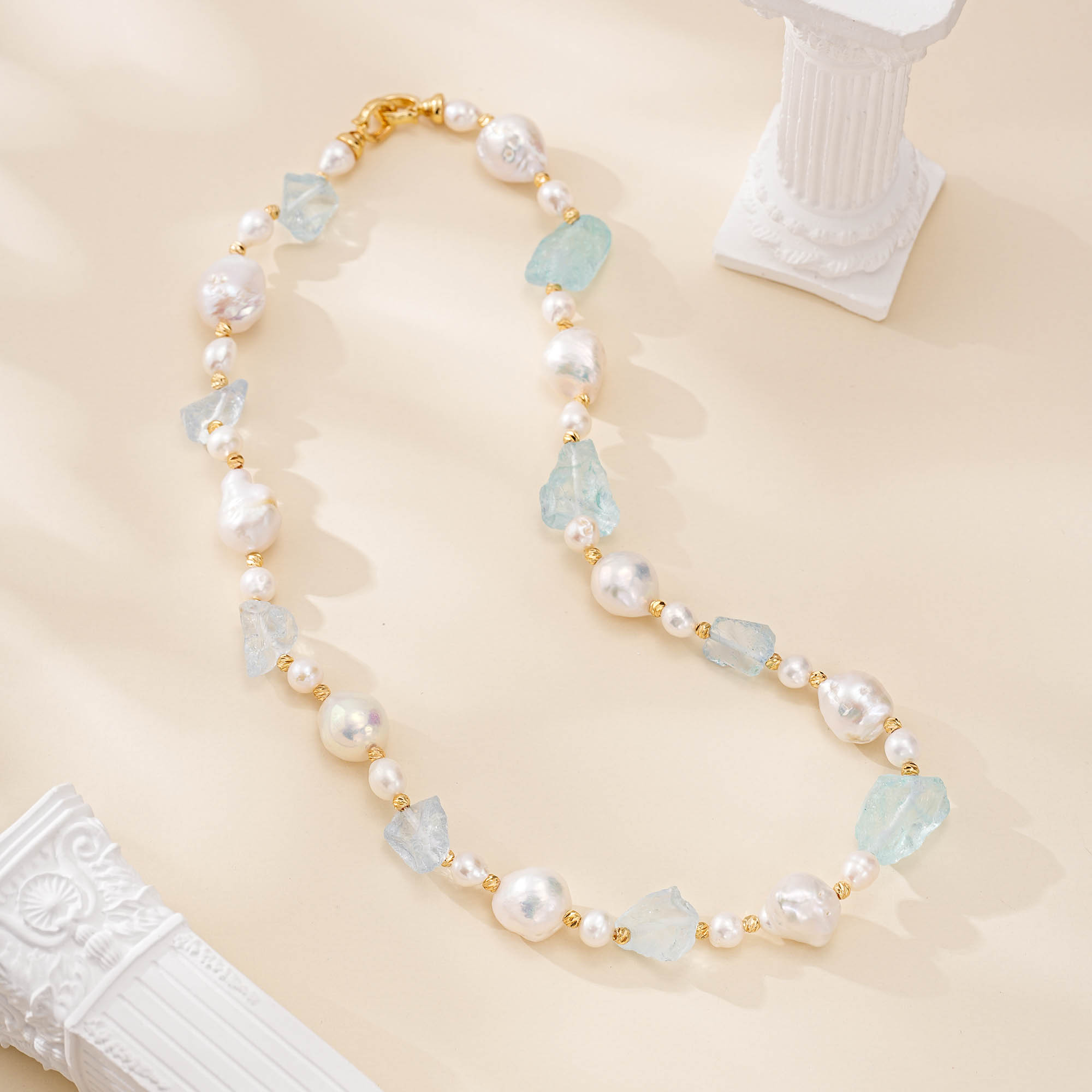 Full aquamarine and baroque pearl necklace laid flat with gold-toned clasp