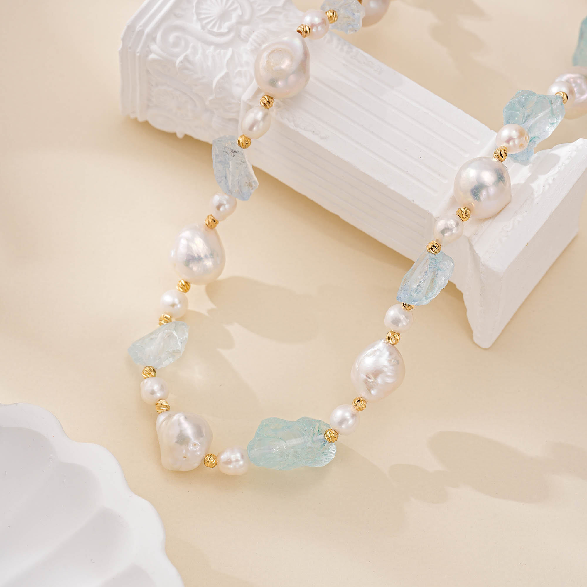 Detail of pale aquamarine stones and irregular baroque pearls in a necklace