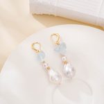 Aquamarine and baroque pearl drop earrings with gold-toned hooks on a white plate