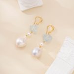 Pair of raw aquamarine and baroque pearl drop earrings laid flat