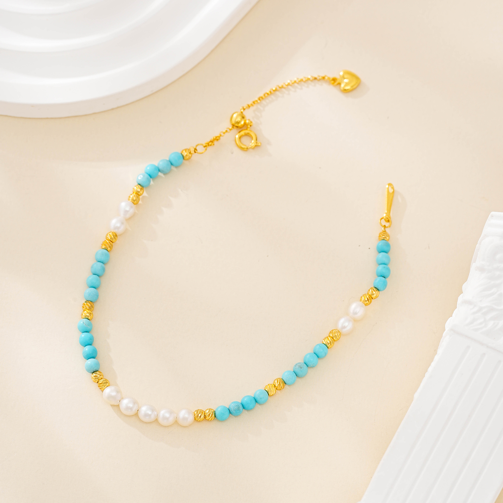 Turquoise bead and freshwater pearl bracelet with gold-tone spacers and extender laid flat