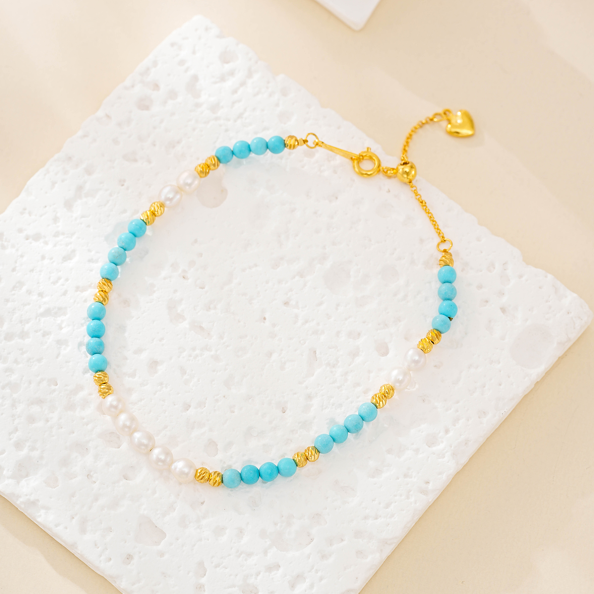 Blue turquoise and white pearl beaded bracelet on a textured white surface