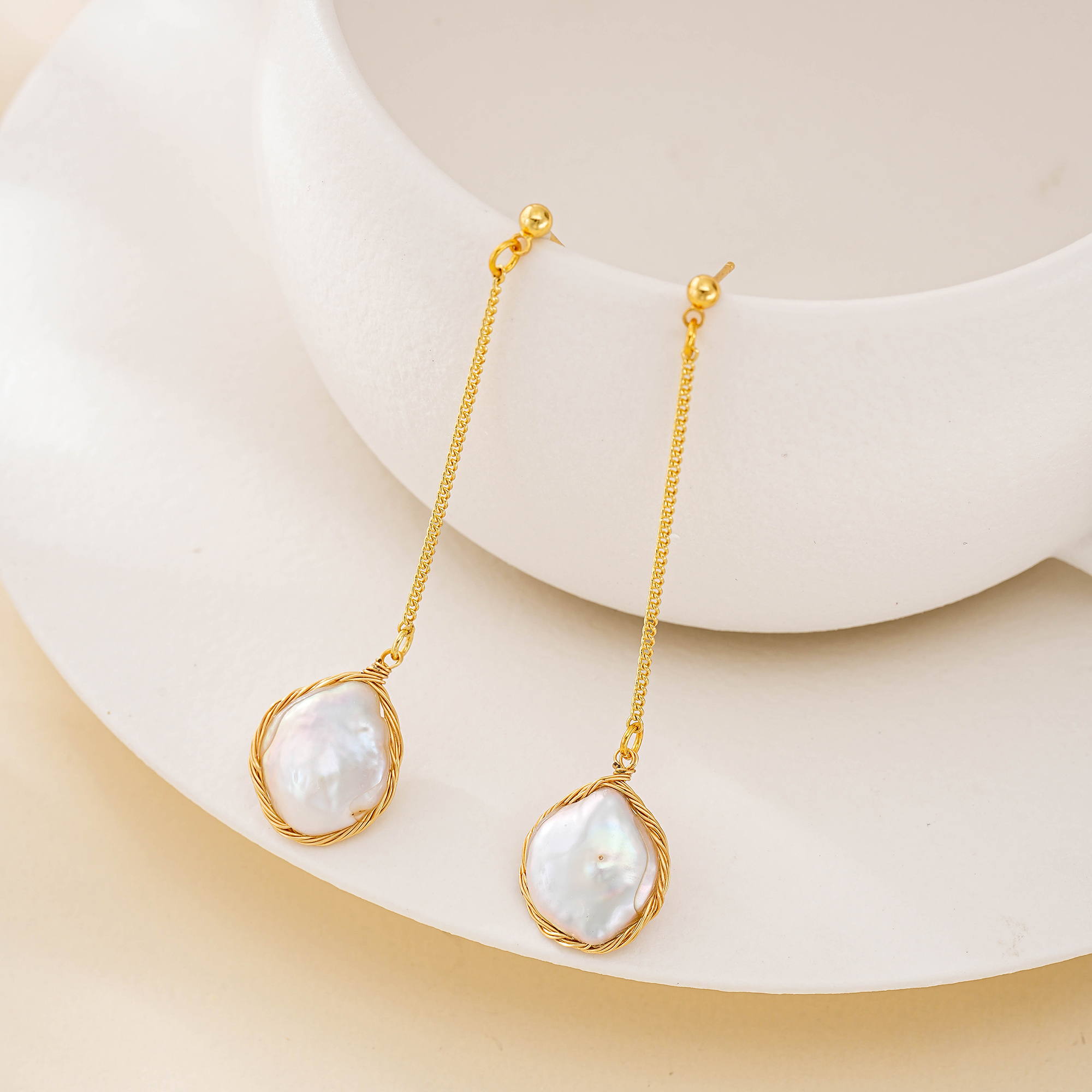 Gold-tone chain drop earrings with wire-framed baroque pearl pendants hanging from stud posts