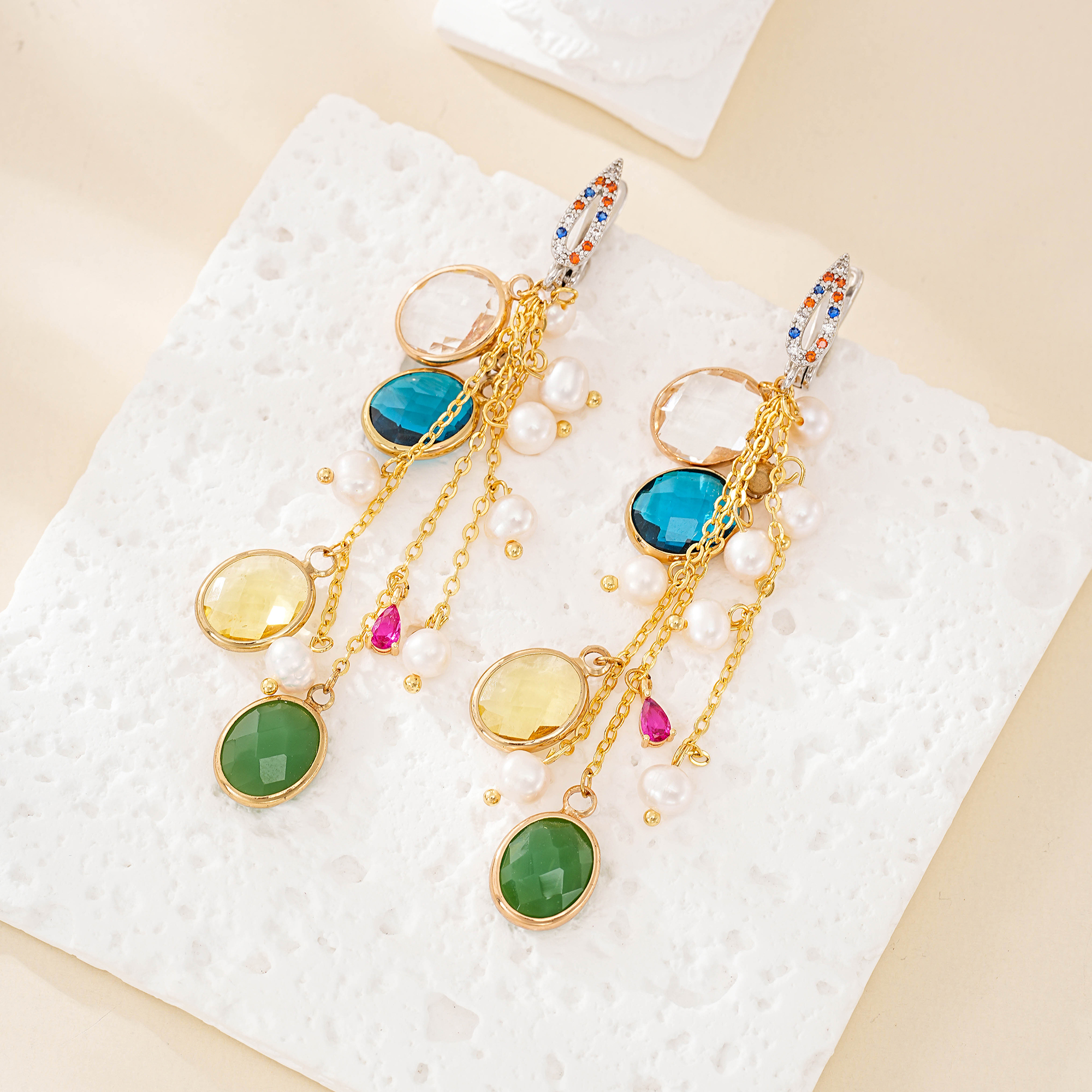 Pair of colorful glass and pearl chain tassel earrings laid flat