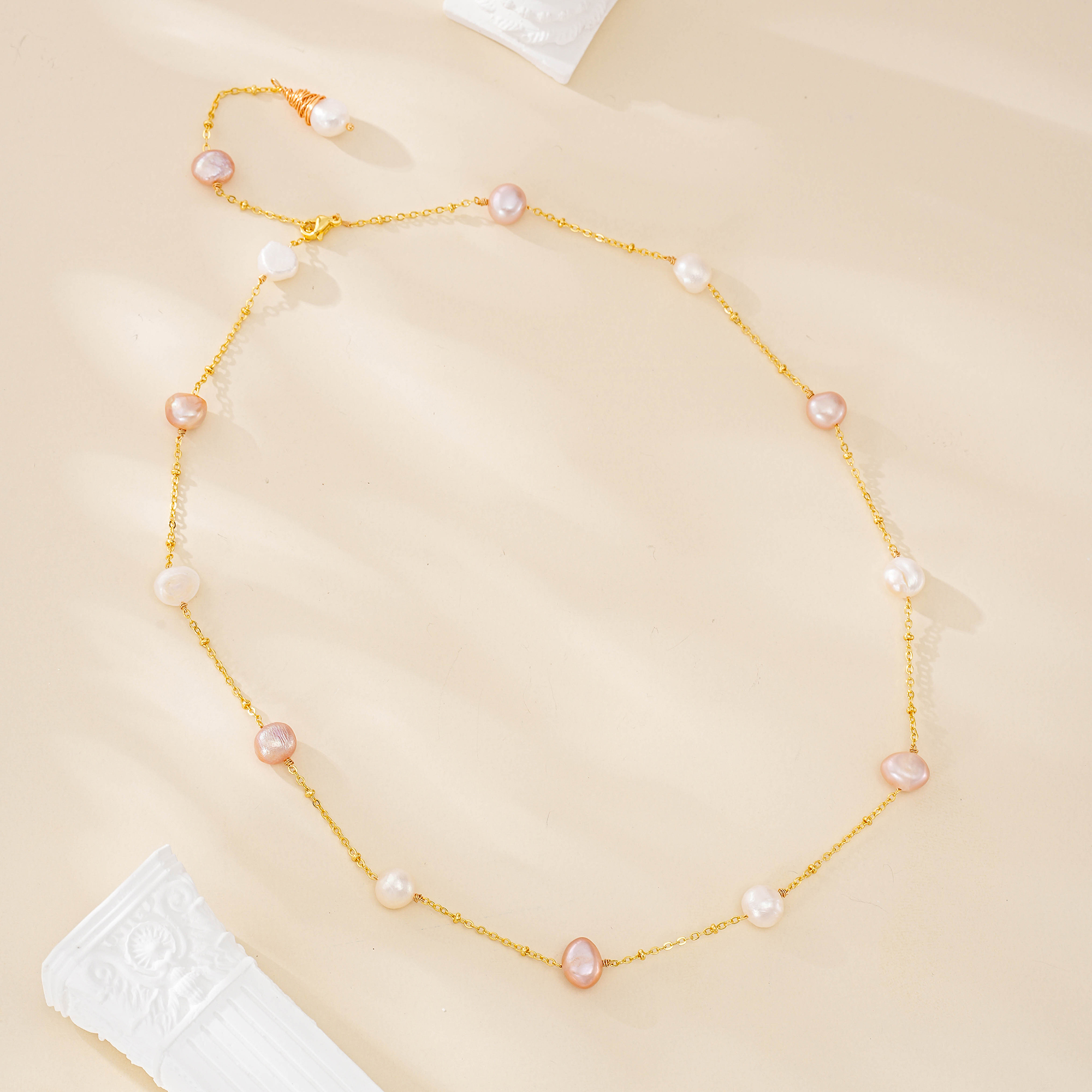 Pink and white freshwater pearl station necklace arranged in a circle