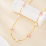 Close view of pink and white pearls spaced along a gold-tone necklace chain
