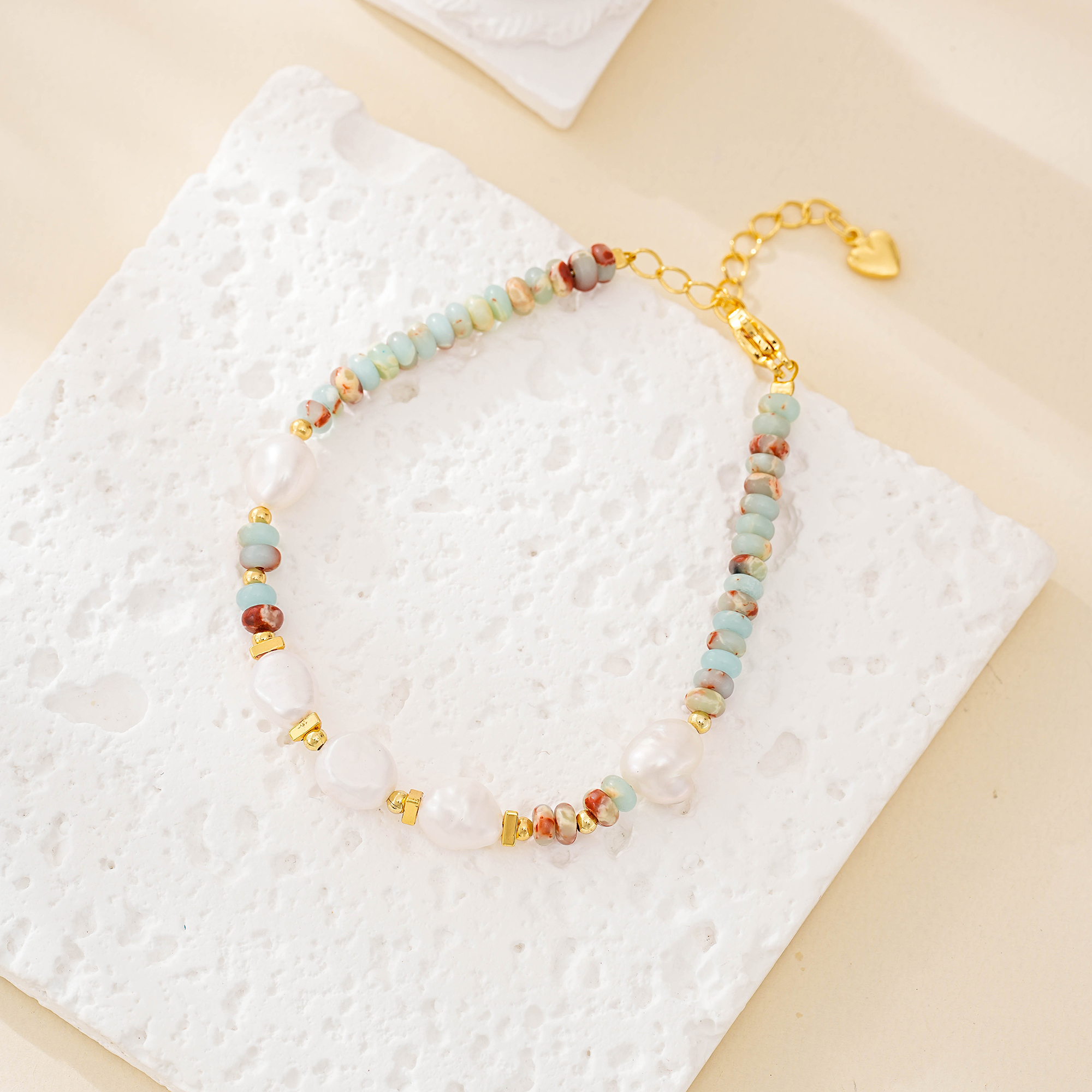 Pastel stone and white pearl beaded bracelet laid flat with gold-tone extender
