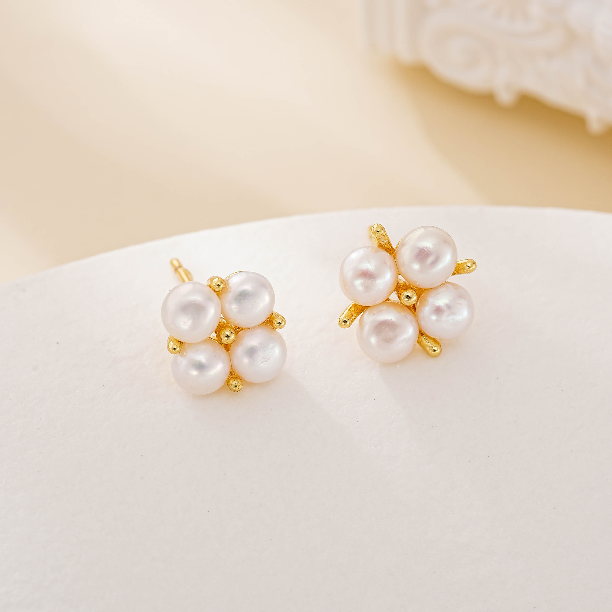 Four round freshwater pearls arranged in flower-like stud earrings