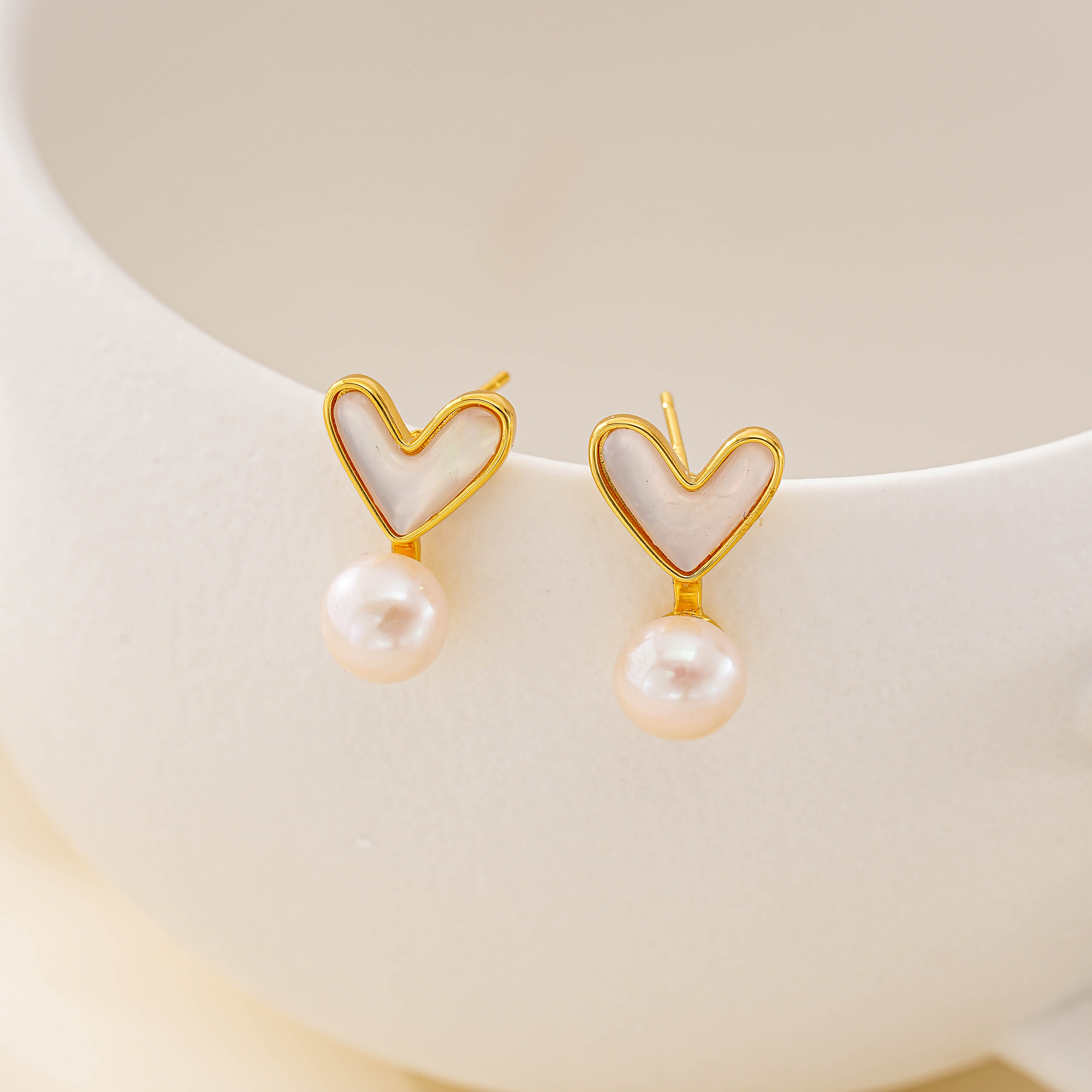Shell heart stud earrings with freshwater pearl drops displayed upright