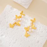 Butterfly pearl cluster drop earrings with gold-tone butterfly charms laid flat