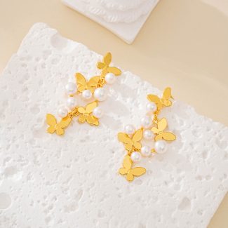 Butterfly pearl cluster drop earrings with gold-tone butterfly charms laid flat