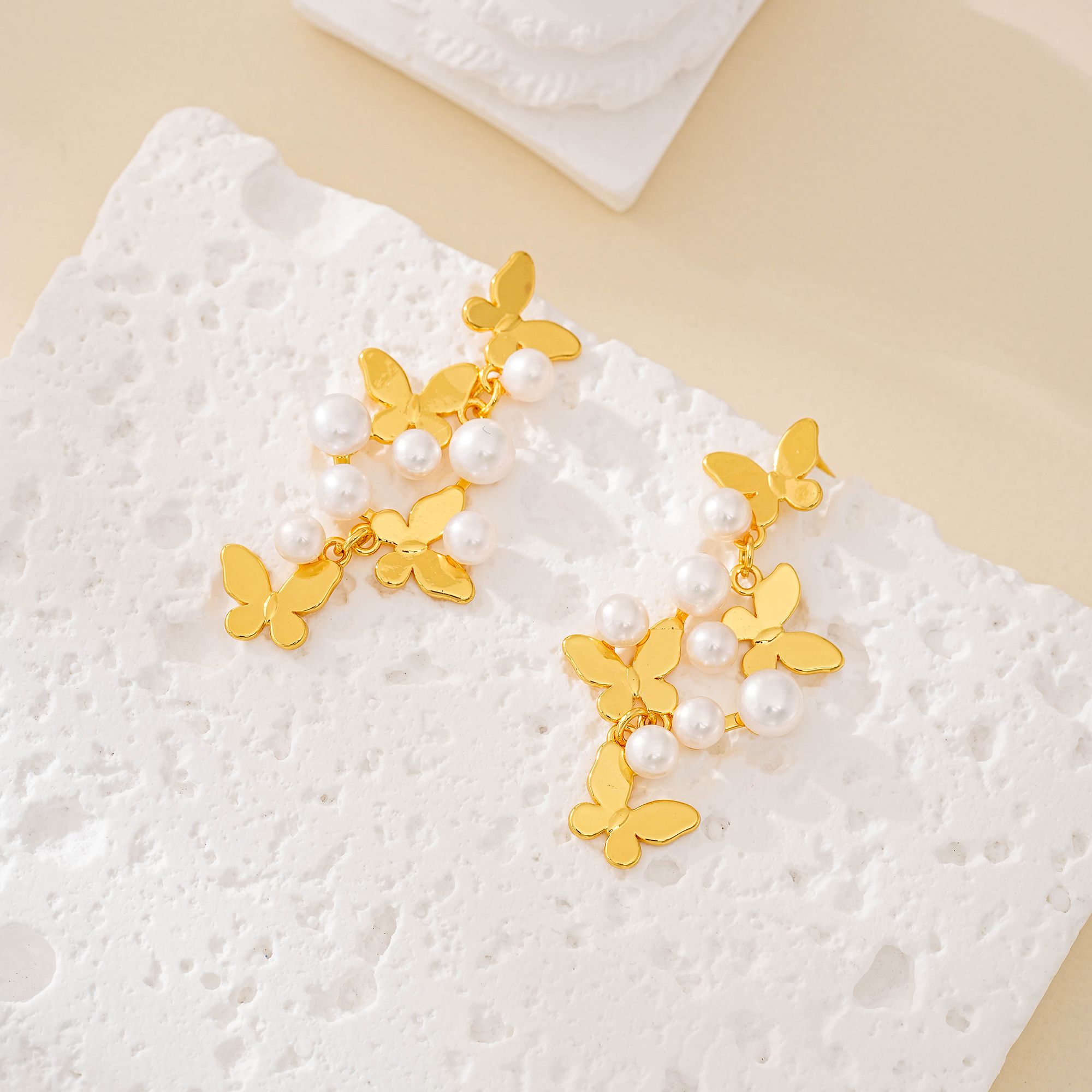 Butterfly pearl cluster drop earrings with gold-tone butterfly charms laid flat