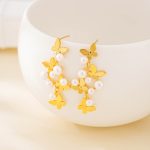 Butterfly and freshwater pearl earrings with gold-tone stud posts on white display