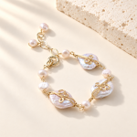 Baroque freshwater pearl link bracelet with curled gold-tone wire settings and pearl charms laid flat