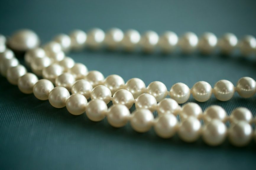 White pearl necklace arranged on soft grey fabric