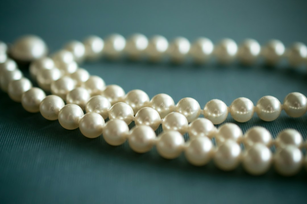 White pearl necklace arranged on soft grey fabric