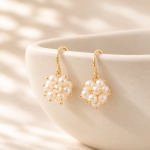 White freshwater pearl cluster drop earrings hanging from patterned gold-plated copper hooks