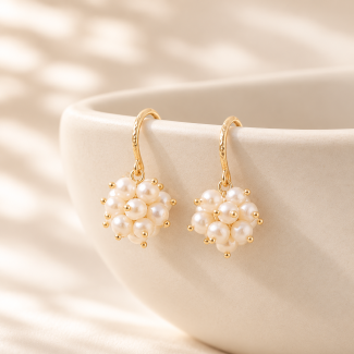 White freshwater pearl cluster drop earrings hanging from patterned gold-plated copper hooks