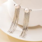 Silver-tone pearl chain tassel earrings hanging from a white display