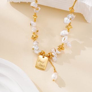 Close-up of irregular pearls and engraved Good Luck necklace charm