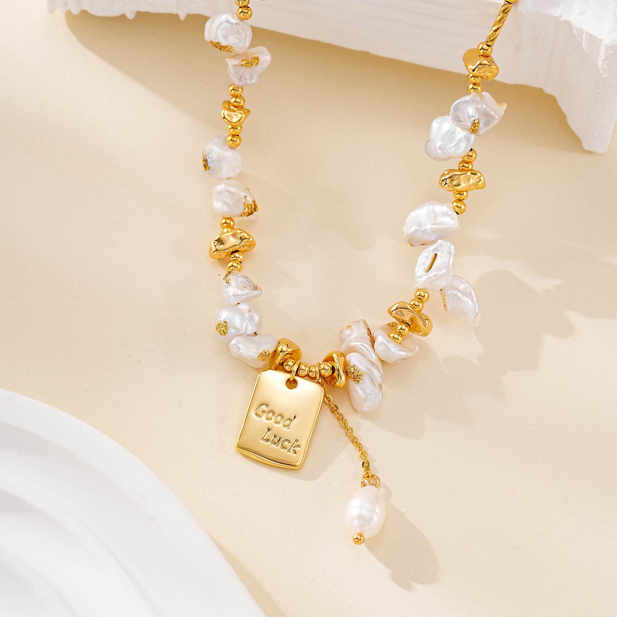 Close-up of irregular pearls and engraved Good Luck necklace charm