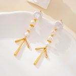 Gold-tone pearl chandelier earrings arranged on a curved white display